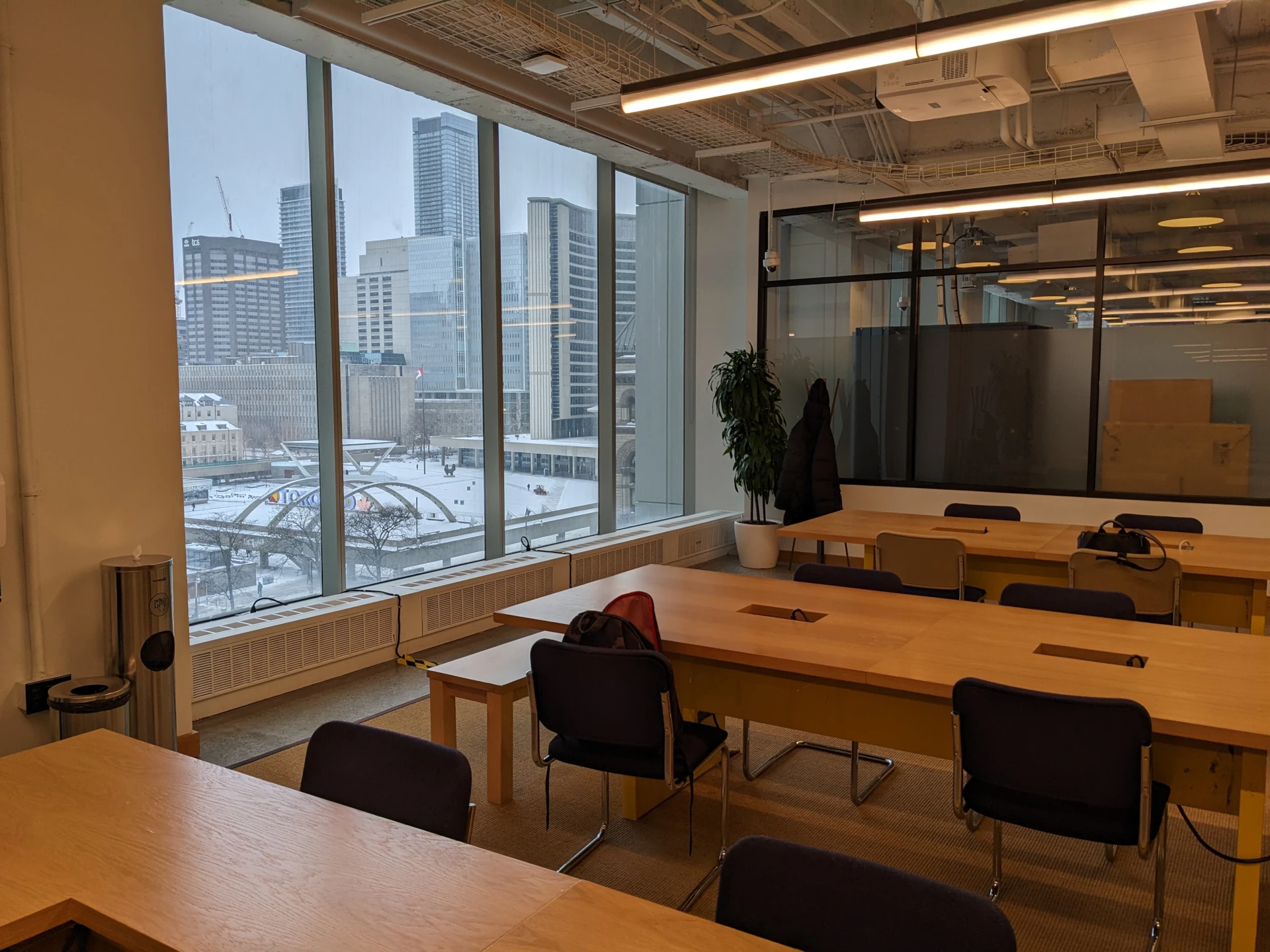 Hotdesks overlooking a snowy Nathan Phillips Square at WeWork at Hudson's Bay, 176 Yonge Street. (This location closed in June 2024.)